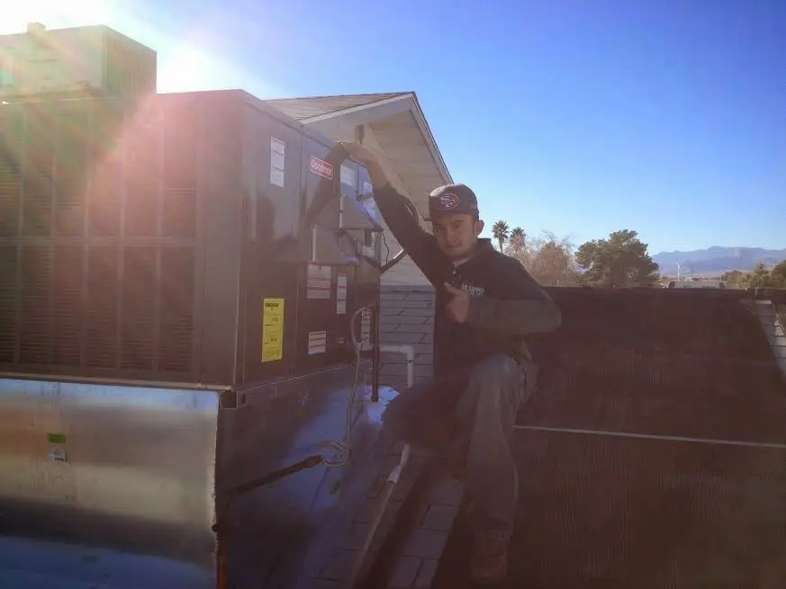 HVAC technician performing Air Duct Cleaning on a rooftop unit in Guadalupe