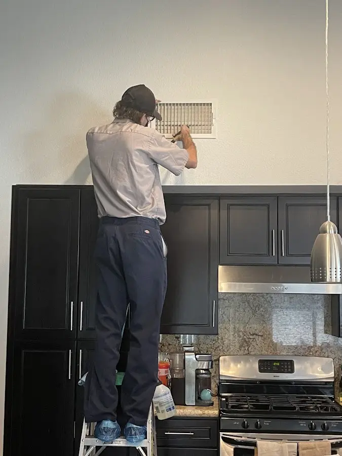 Technician inspecting an air vent during HVAC service in Guadalupe